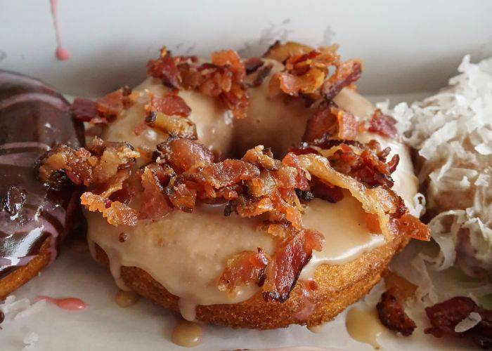 A close-up shot of a maple creme and bacon bits donut.